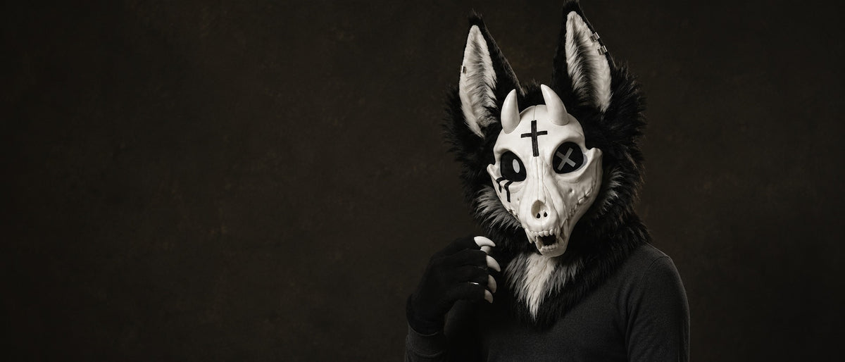 VIGIL — a one-of-one skulldog partial by Fulu Fursuits, bone faceplate and black fur against a warm dark wall
